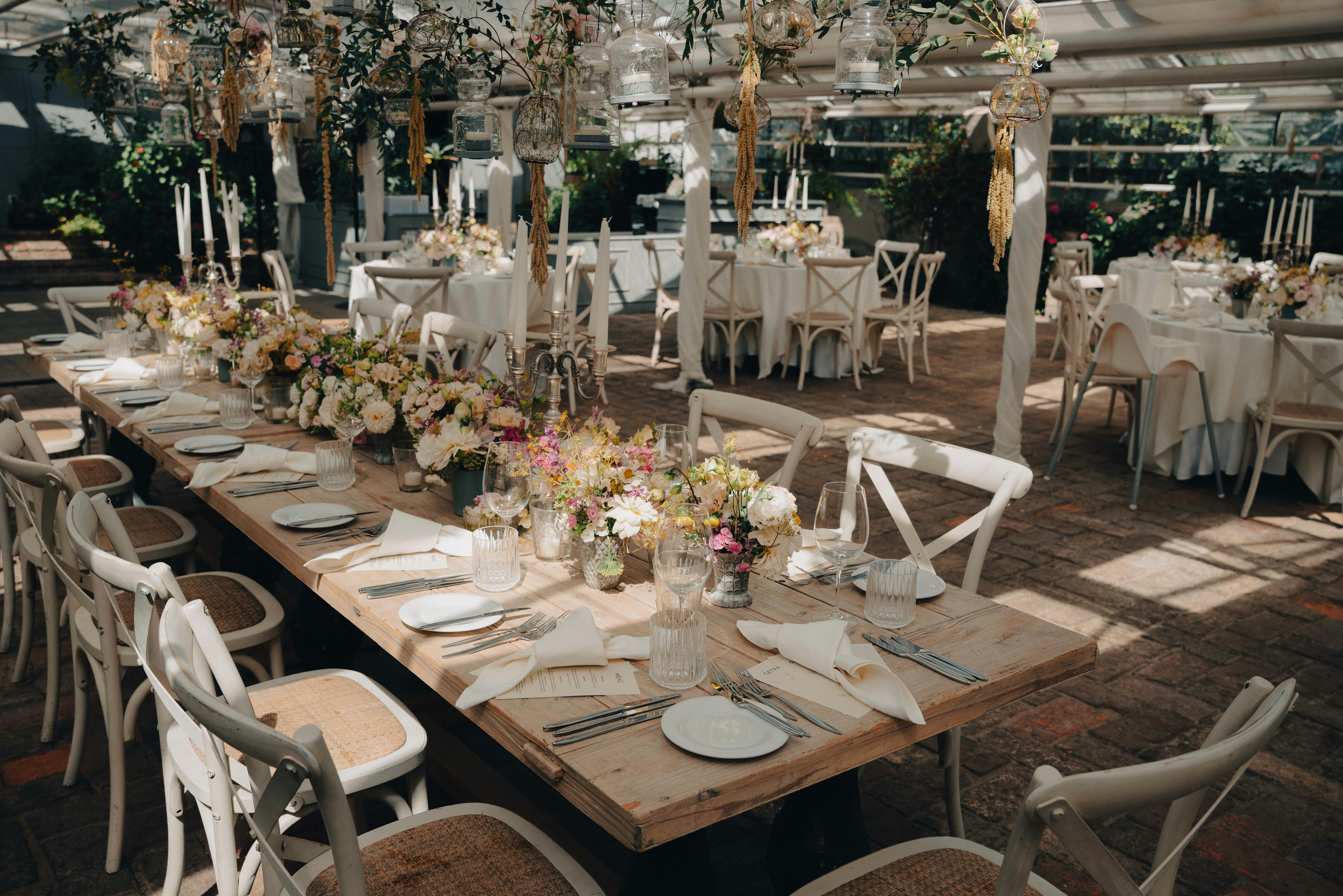 Outdoor garden event setup with gold chairs and floral centerpieces