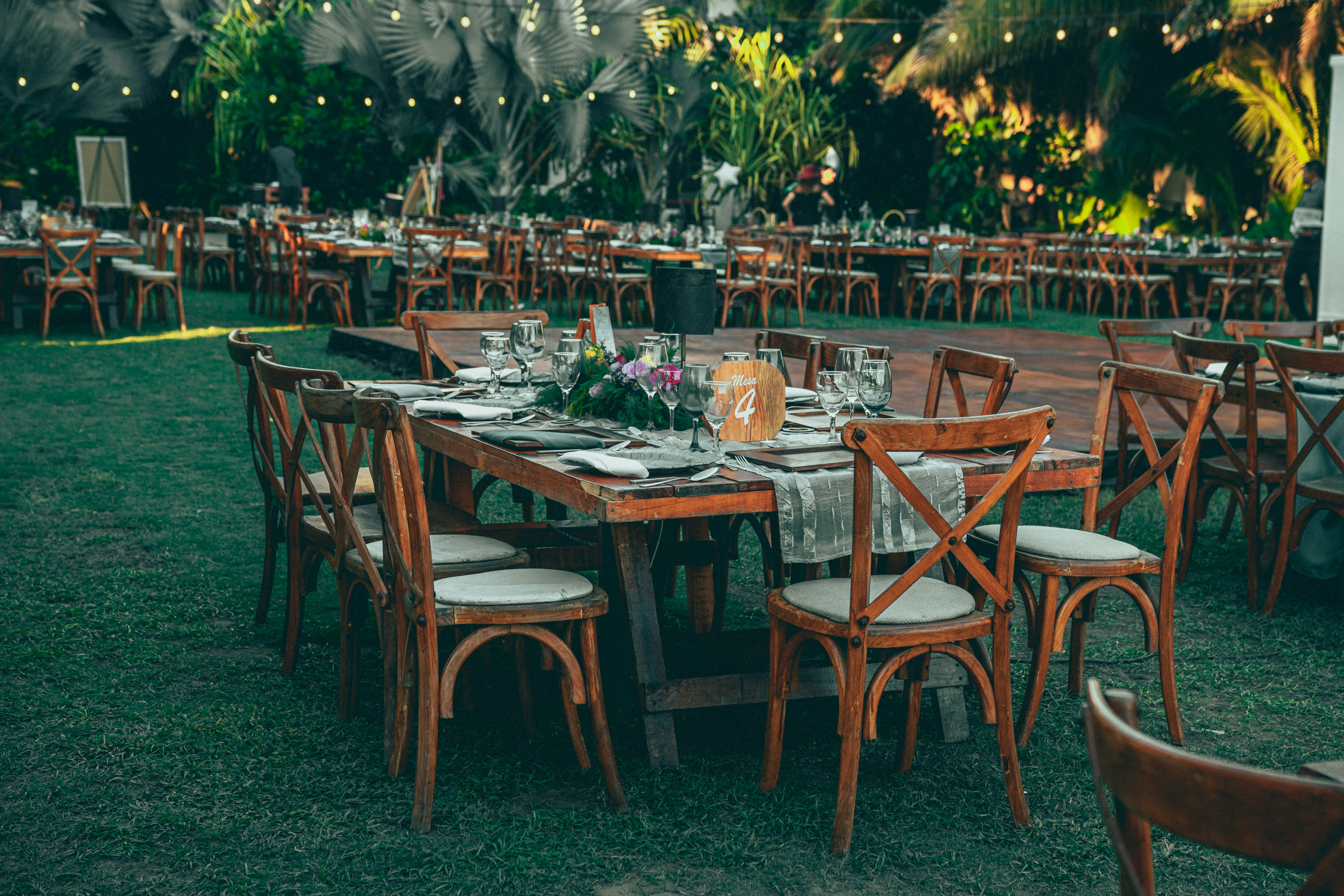 Evening garden reception with wooden dining tables and ambient lighting