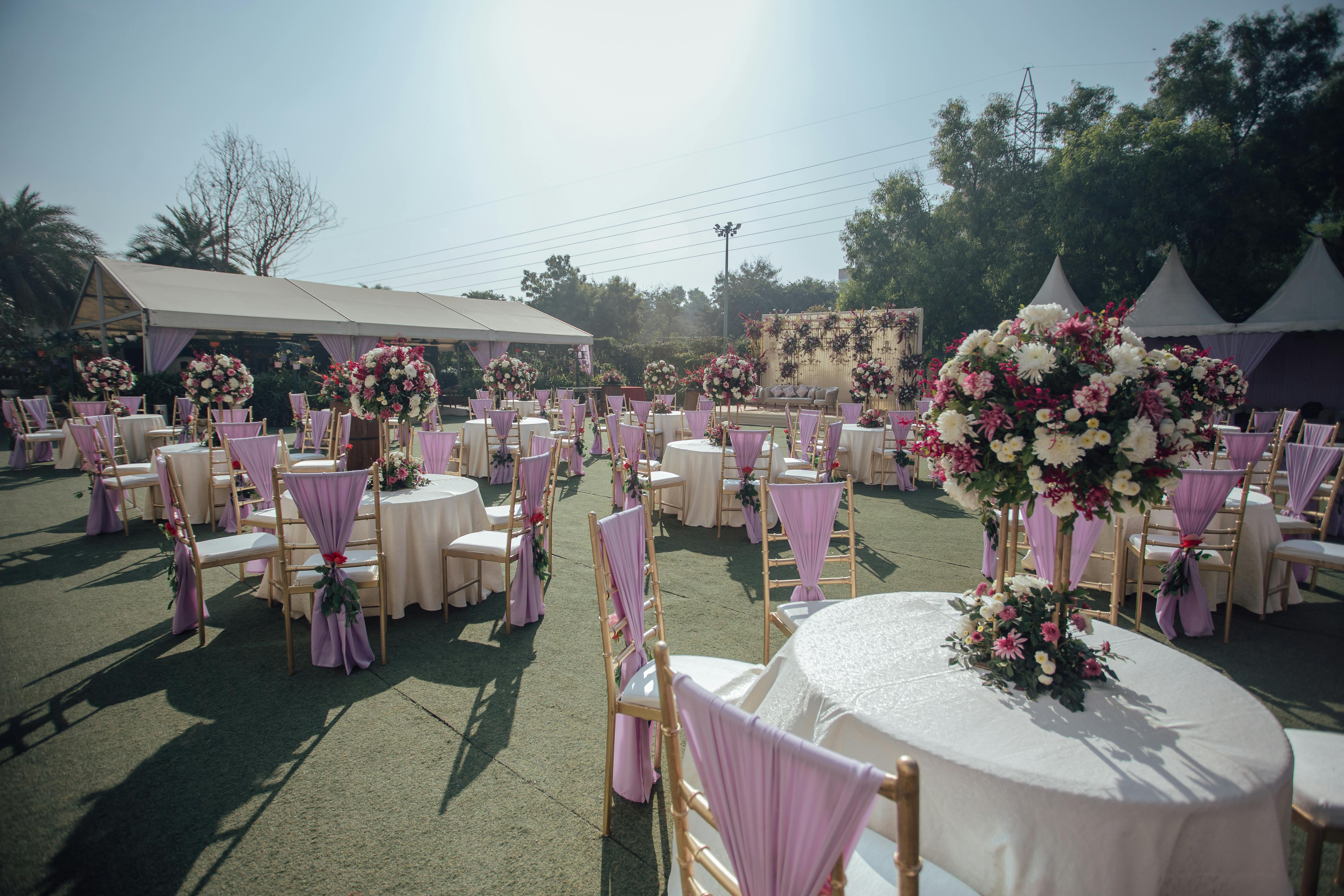 Soft-toned reception space with white folding chairs and round table centerpieces